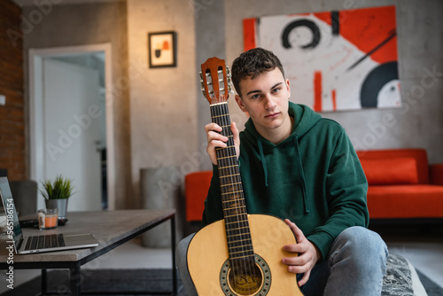 One man caucasian male teenager with classical guitar at home