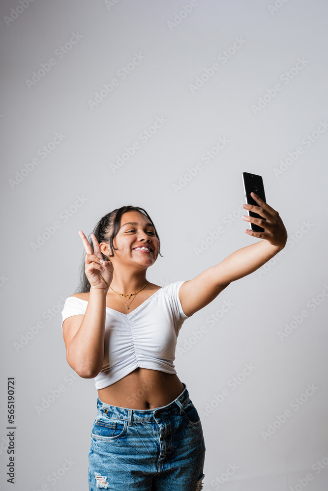 Latin girl taking a picture with her mobile phone. Teenager in a video call  with her