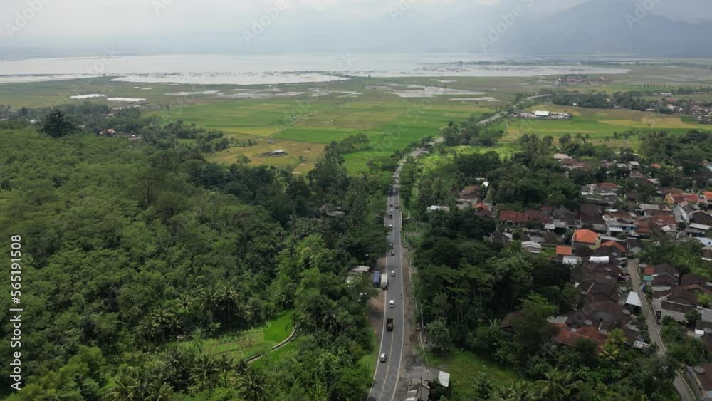 Drone sky view of road tollway highway to the water lake next to the green rain forest and mountain Drone sky view of road tollway highway to the water lake next to the green rain forest and mountain