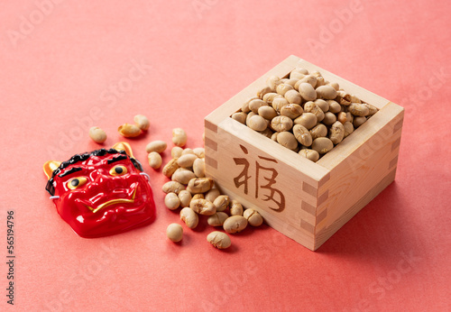 Beans for bean-throwing and masks of ogres placed on a background of red Japanese paper. Japanese ogres. photo