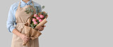 Female florist with bouquet on light background with space for text
