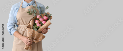 Female florist with bouquet on light background with space for text photo