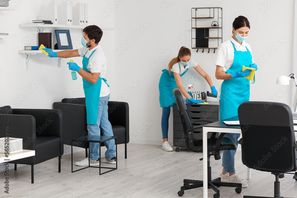 Young janitors with medical masks cleaning in office - obrazy, fototapety, plakaty 