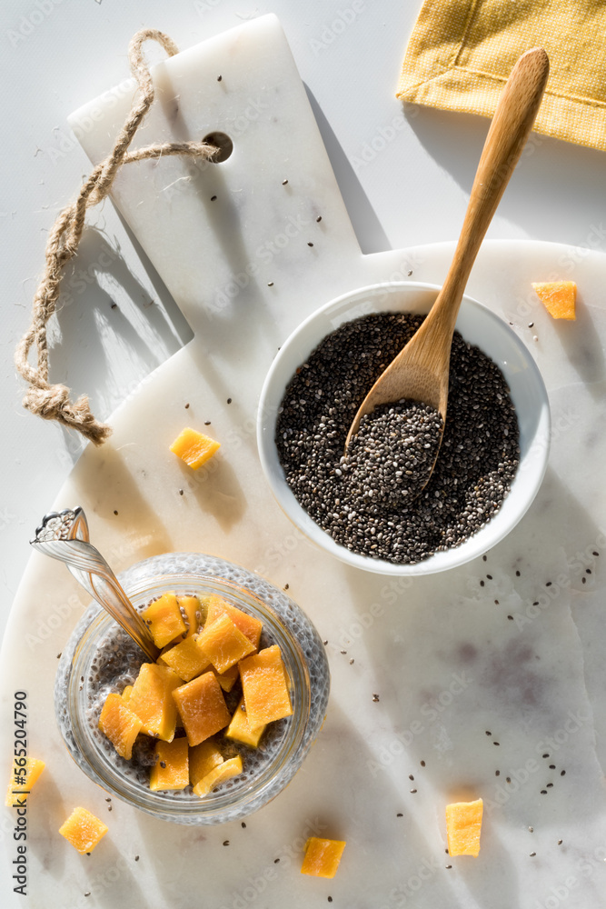Fototapeta premium A mango chia pudding parfait on a marble board with a bowl of chia seeds.