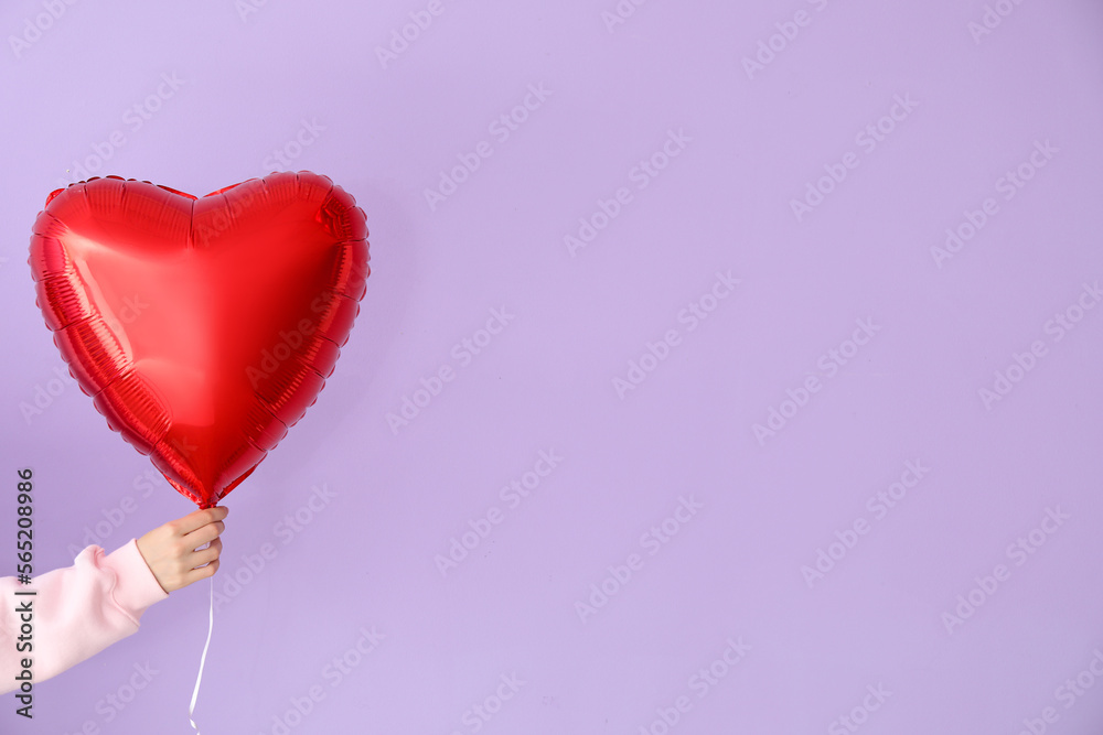 Woman with heart shaped balloon for Valentine's Day on lilac background