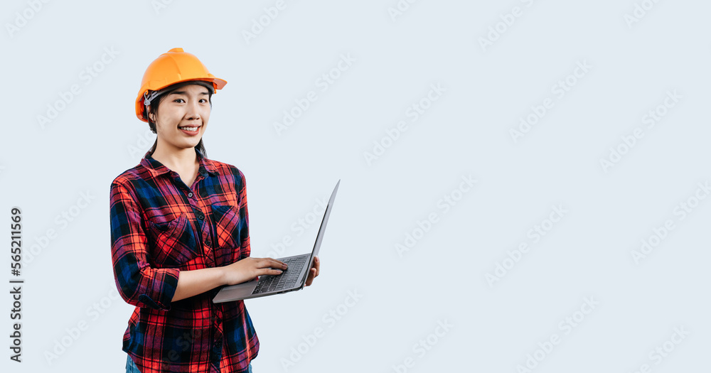 Young female engineer wearing Yellow helmet and use laptop computer