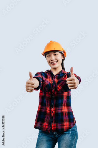 Young female engineer in helmet stand with thumb up posture