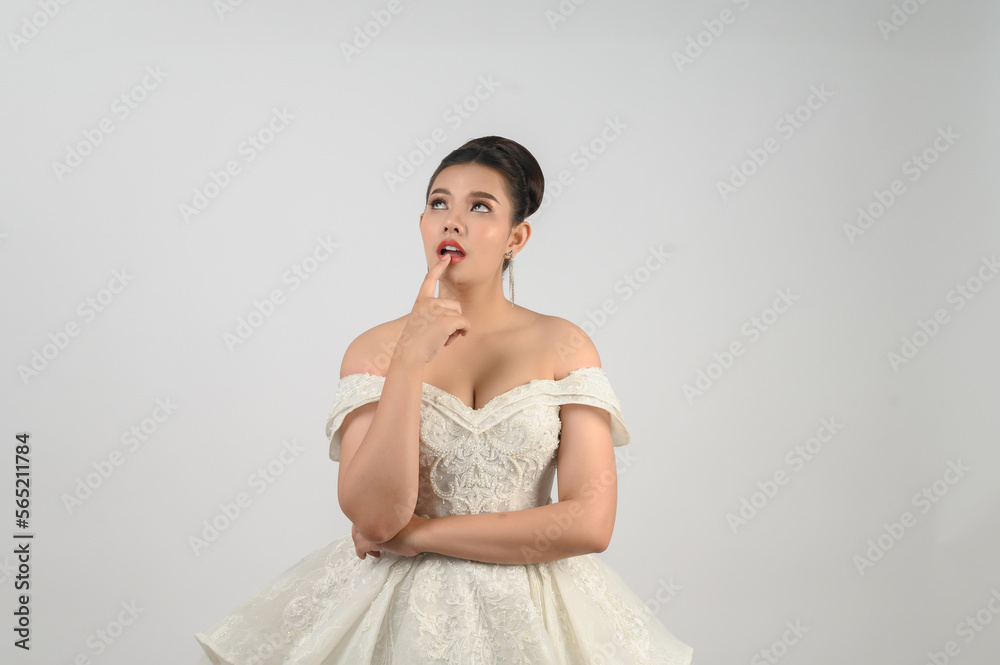 Portrait of beautiful Asian bride in luxurious wedding dress in thoughtful pose Portrait of beautiful Asian bride in luxurious wedding dress in thoughtful pose
