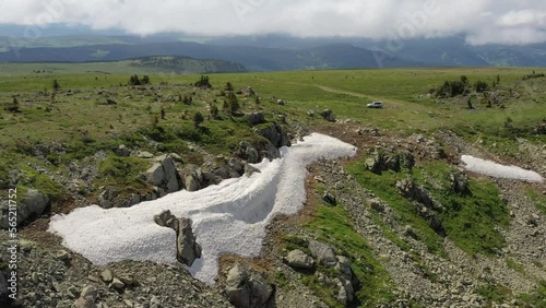 Aerial video of mount Sarlyk slopes. Drone flies along slope with snowfield and rocks. Altai highlands. photo