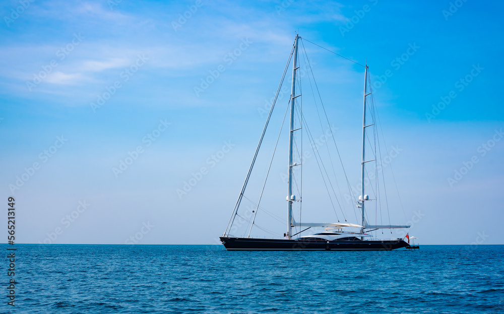 large luxury sailing yacht is anchored off an island in a tropical sea.
