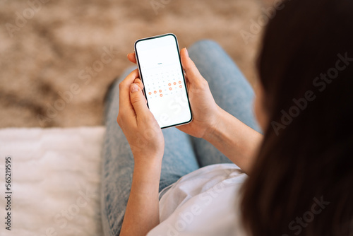 Lady looks in the smartphone days of the calendar menstrual cycle. photo