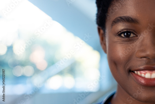 Half face portrait of smiling african american female doctor in hospital corridor with copy space photo