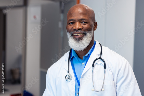Portrait of smiling african american senior male doctor in hospital corridor
