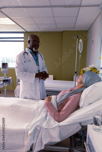 African american male doctor visiting senior caucasian female cancer patient in head scarf
