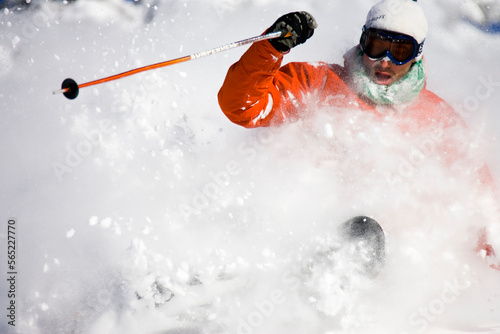 Male skier rides out the perfect powder turn. Mouth wide open as he ingests the powder spray.