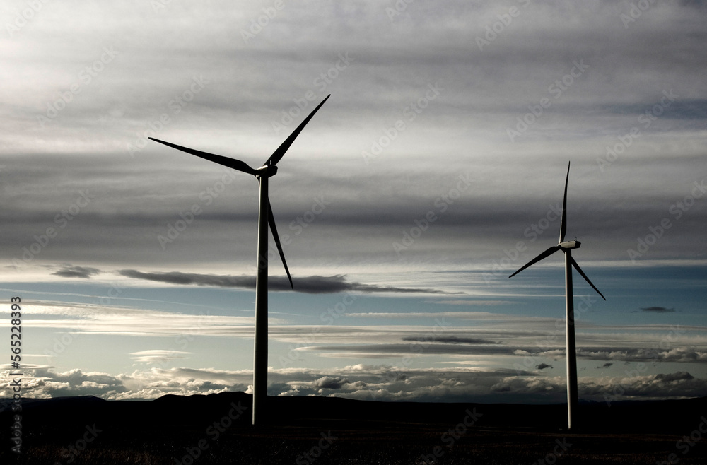 Two windmills spin in a field just before dusk. Two windmills spin in a field just before dusk.