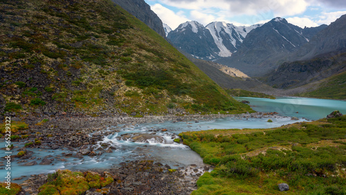 The turquoise water of the Karakabak River flows from the lake among the stones in the Altai mountains.