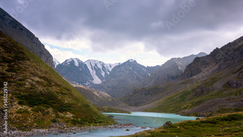 Fototapeta Naklejka Na Ścianę i Meble -  The turquoise water of the Karakabak River flows out of the lake among the stones in the Altai mountains under thick clouds.