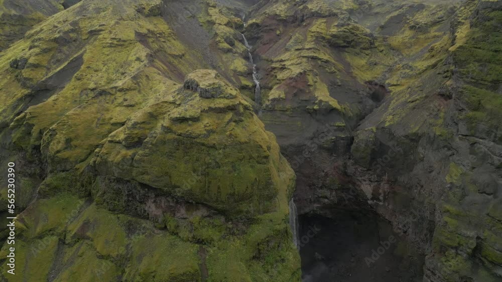 Waterfall drone shot as water drops aggressively over a rocky greenish-yellow ledge into a plunge pool below. PANNING DOWN Waterfall drone shot as water drops aggressively over a rocky greenish-yellow ledge into a plunge pool below. PANNING DOWN