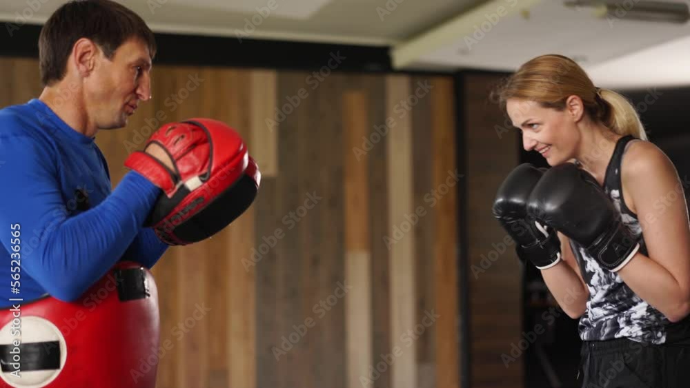 Coach giving a private training to a female athlete practicing punches. Training sparring of female kickboxer and male trainer practicing punches and kicks. Girl boxing in urban gym. Feminist concept Coach giving a private training to a female athlete practicing punches. Training sparring of female kickboxer and male trainer practicing punches and kicks. Girl boxing in urban gym. Feminist concept