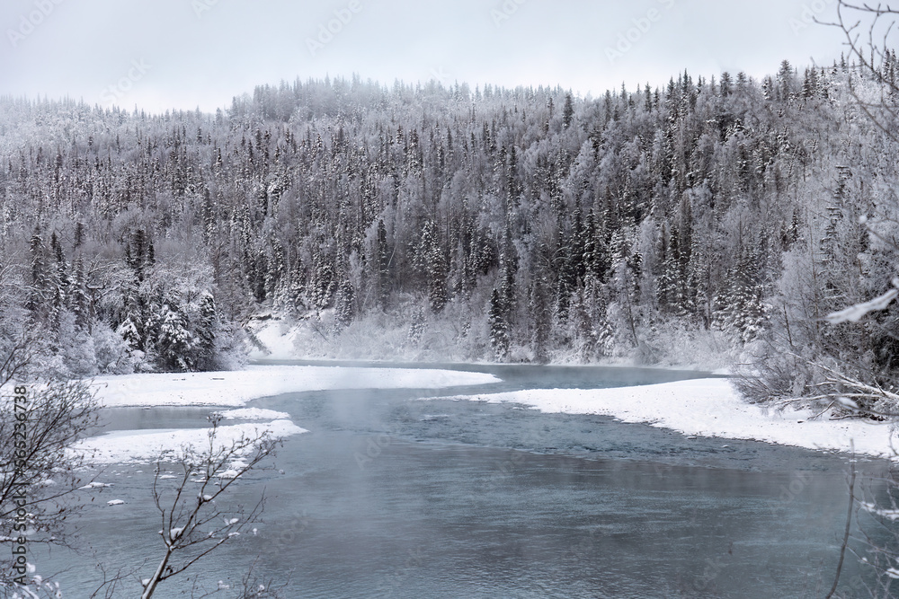 Alaska river in winter as steam rises along the forest channel