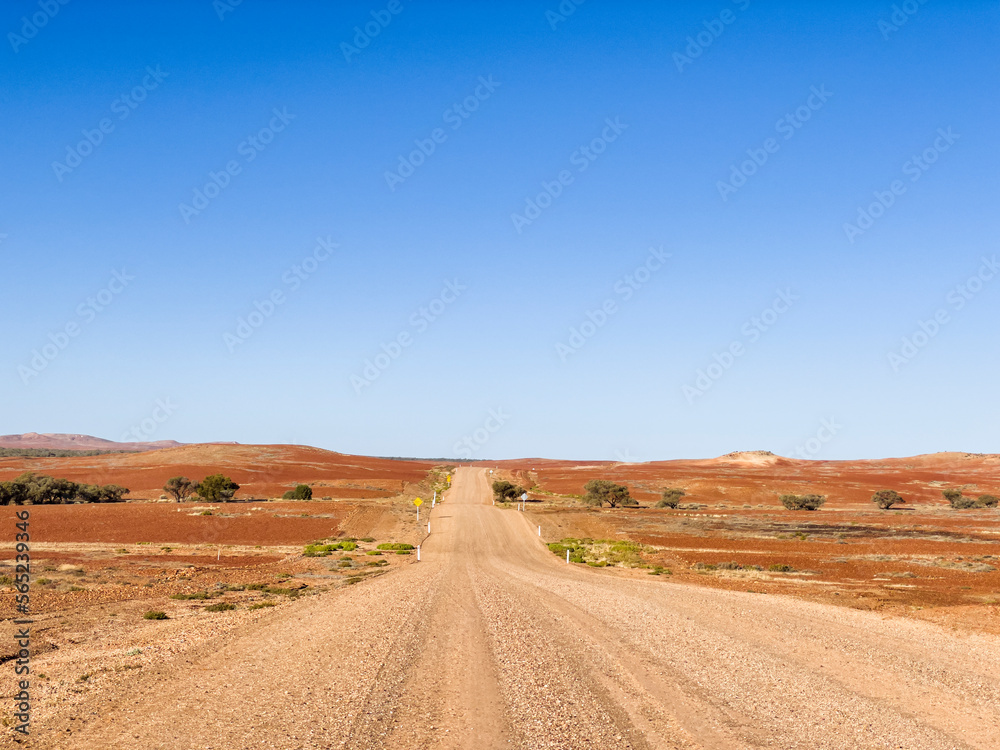 Outback desert dirt road with blue sky, Northern Territory, Australia.