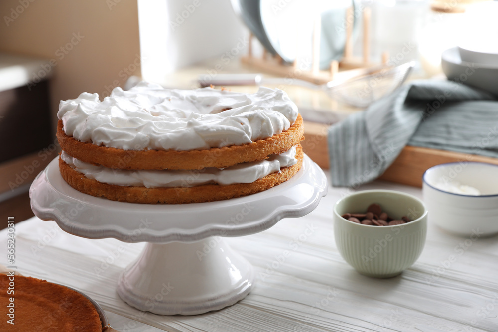 Delicious homemade sponge cakes with cream on white wooden table in kitchen. Space for text