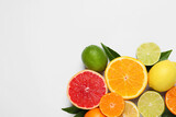 Different citrus fruits with fresh leaves on white background, top view. Space for text
