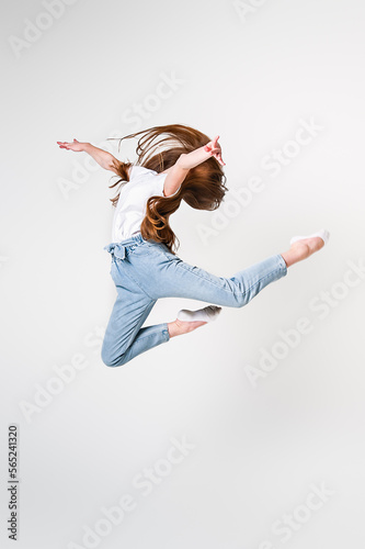 A teenage girl in jeans and a white T-shirt performs dance moves. White background