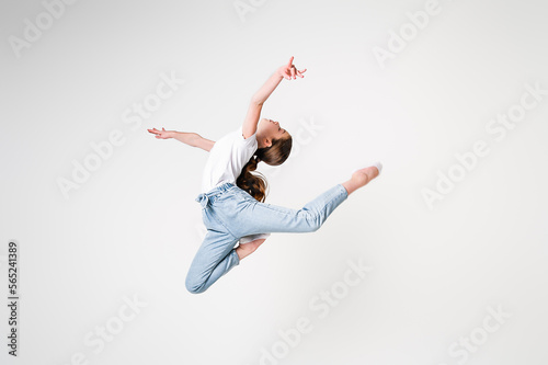 A teenage girl in jeans and a white T-shirt performs dance moves. White background