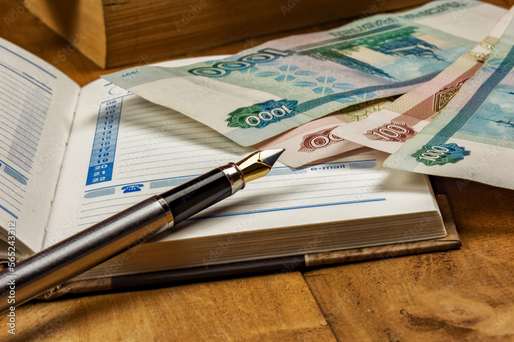Fototapeta premium On the open diary page there are several monetary denominations and a fountain pen