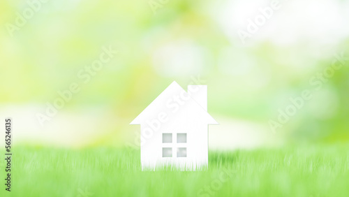 芝生の上の白い小さいおもちゃの家。住宅、不動産、戸建て、新生活のイメージ。（横長）