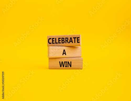 Celebrate a win symbol. Concept words Celebrate a win on wooden blocks. Beautiful yellow background. Business and Celebrate a win concept. Copy space.