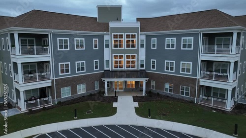 Aerial rising shot of retirement home assisted living building at dusk. Lights on inside of elderly care facility in America. photo