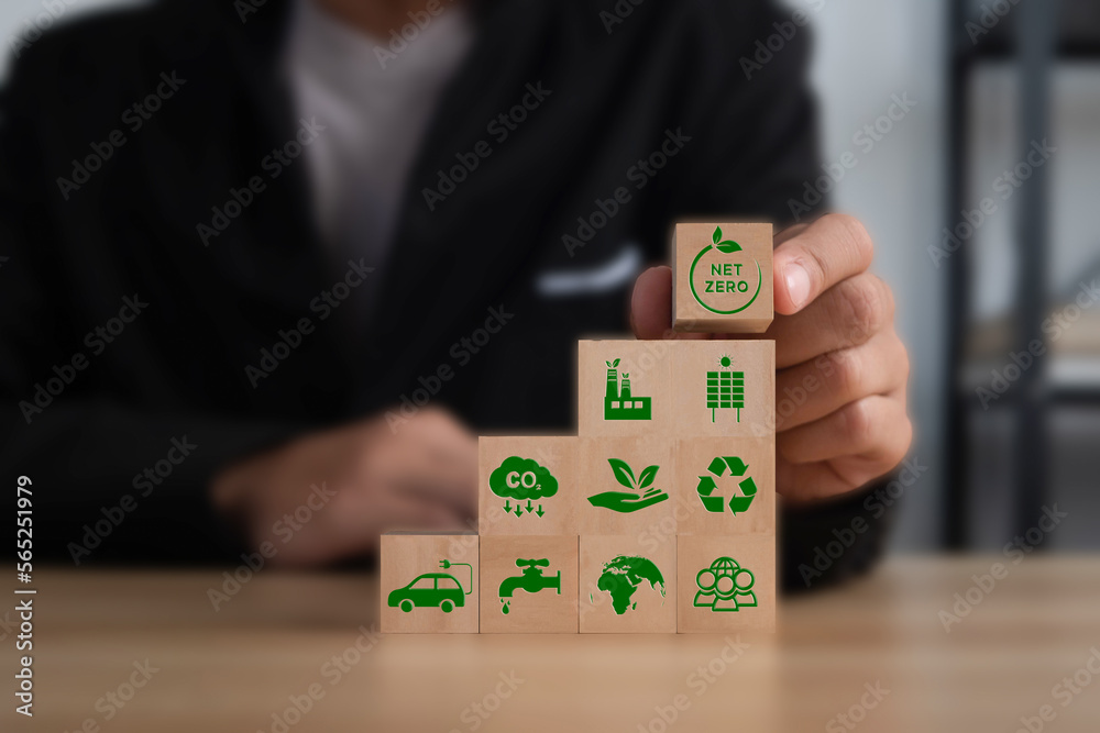 Businessman puting wooden cubes with green net zero icon on table. Net zero and carbon neutral concept. Net zero greenhouse gas emissions target. Climate neutral long term strategy. Businessman puting wooden cubes with green net zero icon on table. Net zero and carbon neutral concept. Net zero greenhouse gas emissions target. Climate neutral long term strategy.