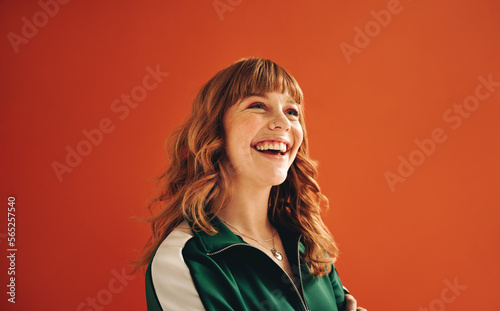 Happy young woman looking away with a smile while standing in a studio photo