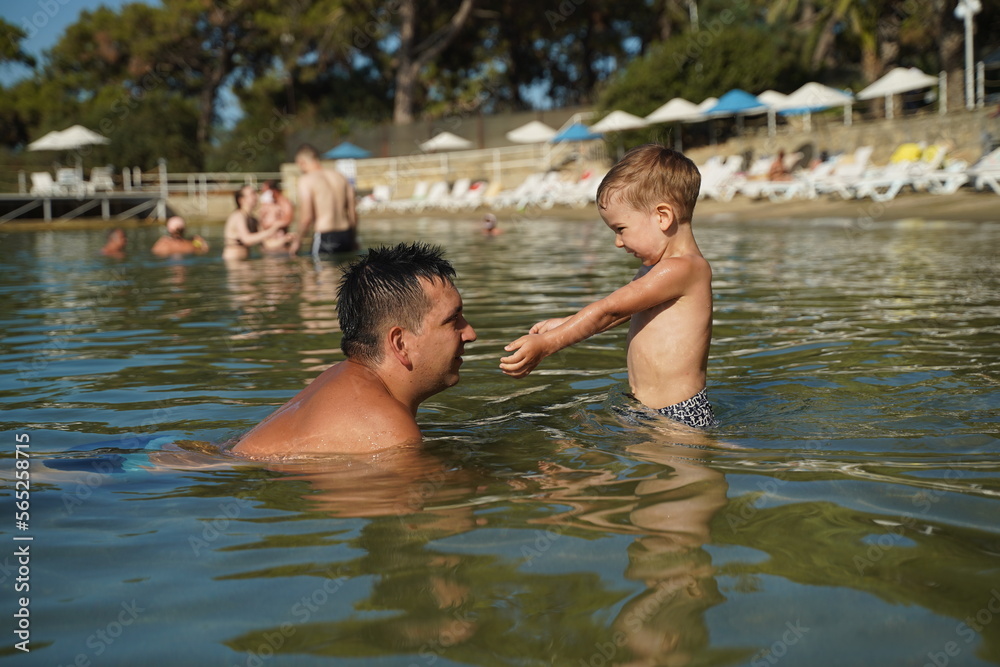 Fototapeta premium Father play in water with his son. Summer vacation, happy family play at beach