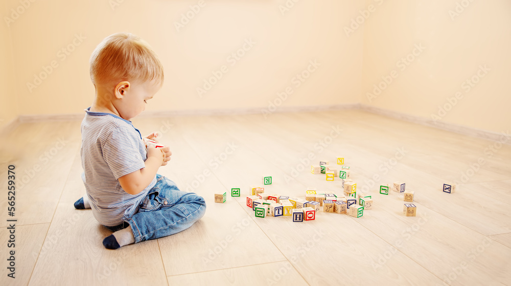 Little boy sitting on the floor indoor and playing with wooden cubes. Little boy sitting on the floor indoor and playing with wooden cubes.