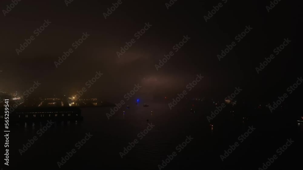 Independence day fireworks exploding over misty San Francisco bay, California aerial view across marina at night