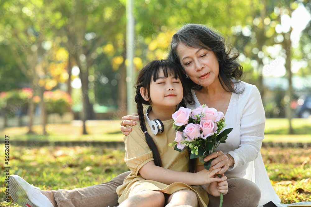 Cute little girl and grandmother holding bouquet of pink roses in hands, enjoying carefree leisure weekend together outdoor Cute little girl and grandmother holding bouquet of pink roses in hands, enjoying carefree leisure weekend together outdoor