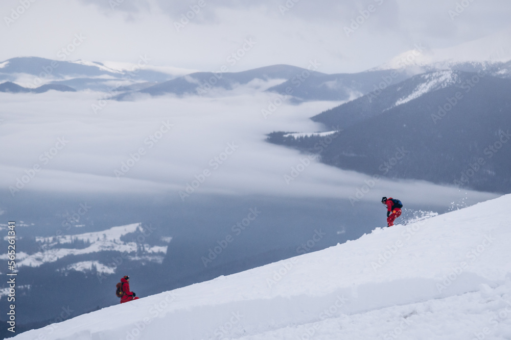 The skier rides high in the snow in the mountains. Fog on the mountain and people skiing