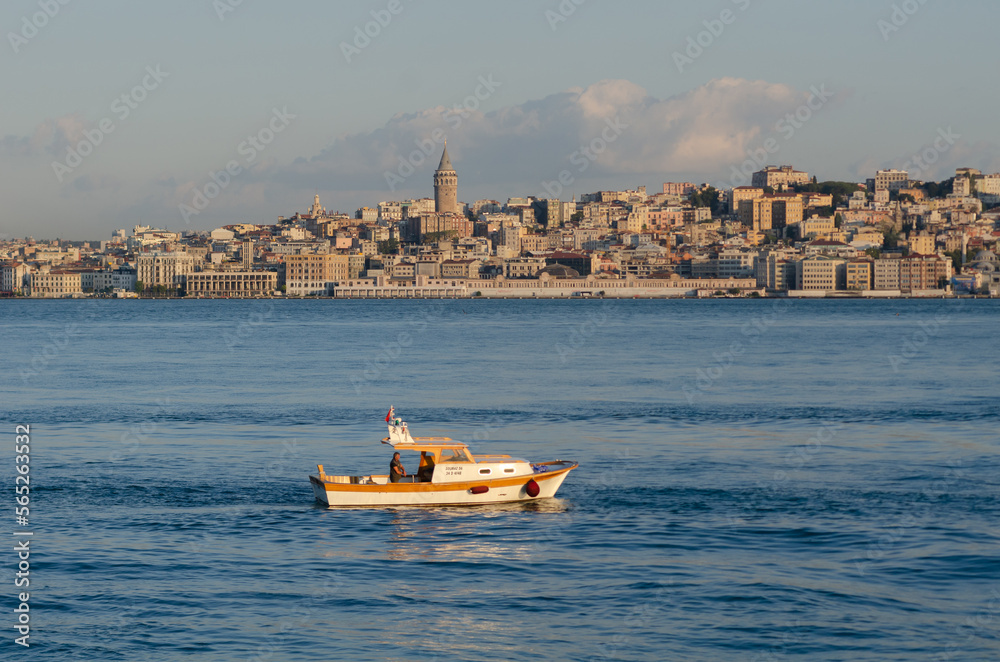 A small fishing boat on the Bosporus straight with the Galata Tower and European Istanbul skyline, Turkey..
