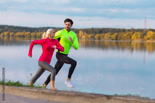 Running Couple While Training Outdoors on Road At River For Durable Marathon Pretty Young Female and Extremely Fit Caucasian Handsome Man. © danmorgan12