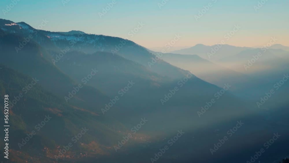 Sun rays coming through the mountains of the Himalayan mountain range of Kullu valley during the sunset as seen from the top of a mountain peak at Manali in Himachal Pradesh, India. Evening background Sun rays coming through the mountains of the Himalayan mountain range of Kullu valley during the sunset as seen from the top of a mountain peak at Manali in Himachal Pradesh, India. Evening background