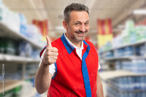 Happy supermarket worker showing thumbs-up sign
