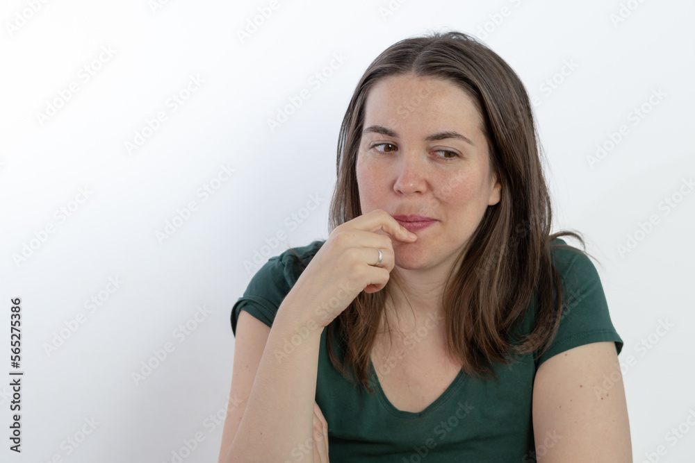 pensive woman looking at the ground with her finger in her mouth pensive woman looking at the ground with her finger in her mouth