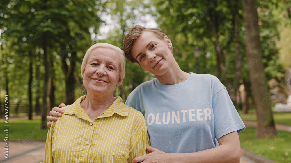 Portrait of woman volunteer and happy aged woman smiling on camera, nursing home, help