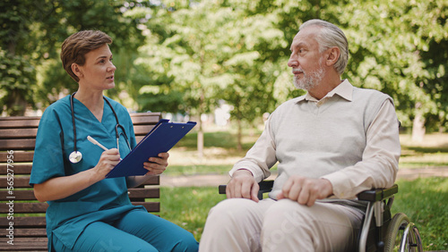 General practitioner asking aged male patient questions, filling in papers with anamnesis
