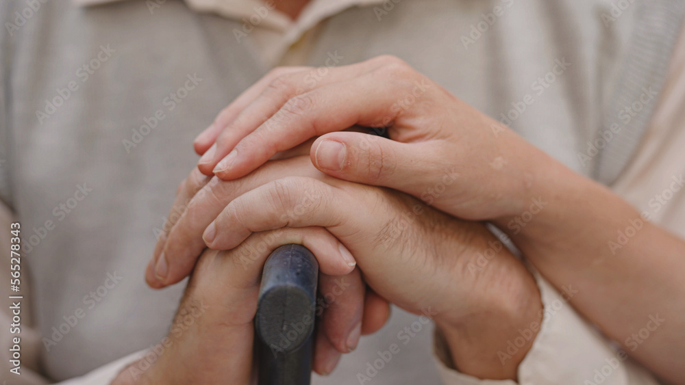 Close-up of woman holding hand of upset old man with a walking stick, family care