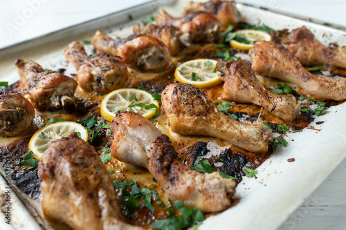 Harissa chicken drumsticks oven baked with lemon and herbs on a baking sheet